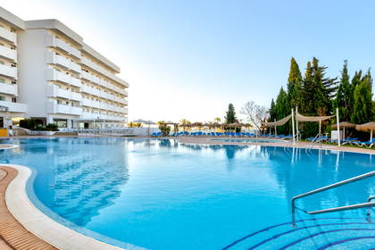 Basen hotelowy z leżakami i parasolami.