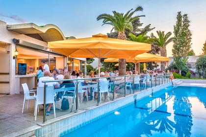 Restauracja na świeżym powietrzu z basenem i palmami.