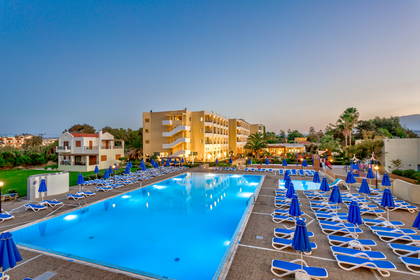 Hotel z basenem, leżakami i parasolami.