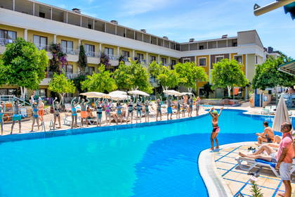 Hotelowy basen. Grupa osób ćwiczy przy brzegu.