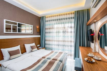 Pokój hotelowy z dwoma łóżkami, zasłonami i stolikiem z jedzeniem.