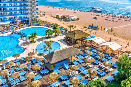 Hotel z basenami, leżakami i parasolami blisko plaży. Widok z góry.