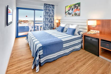 Pokój hotelowy z balkonem i widokiem na morze. W pokoju znajduje się łóżko.