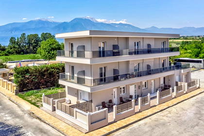 Trzypiętrowy apartamentowiec na tle gór, widok z góry.
