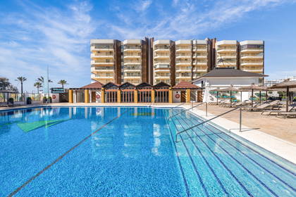 Basen hotelowy z leżakami. W tle budynek.