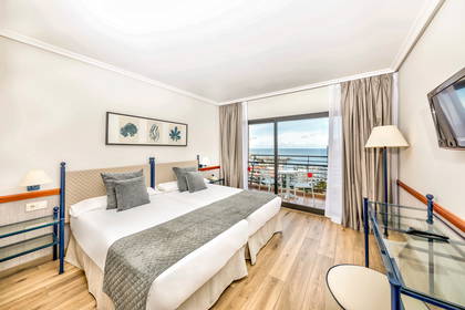 Pokój hotelowy z balkonem i widokiem na morze.