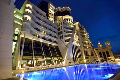 Nowoczesny hotel z basenem oświetlony nocą.