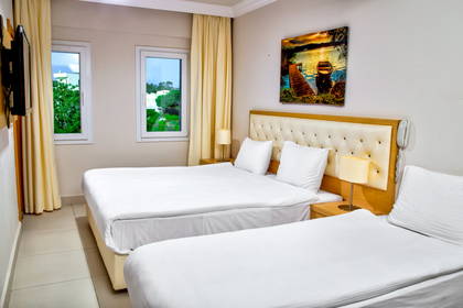 Pokój hotelowy z dwoma łóżkami, oknami i obrazem na ścianie.