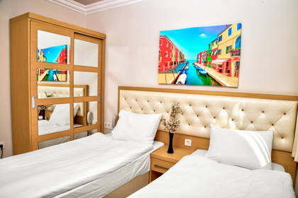 Pokój hotelowy z dwoma łóżkami, szafą z lustrami i obrazem przedstawiającym Wenecję.