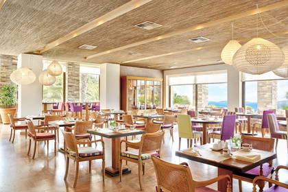 Restauracja z widokiem na morze i nakrytymi stolikami.