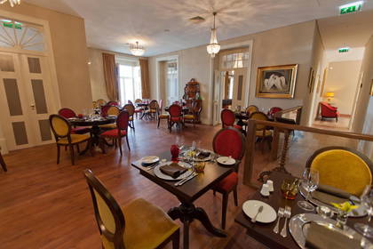 Elegancka restauracja z nakrytymi stołami i żyrandolami.