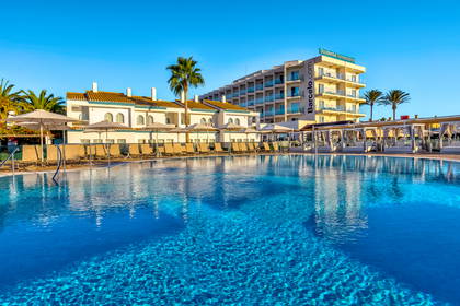 Hotel z basenem, leżakami i palmami.