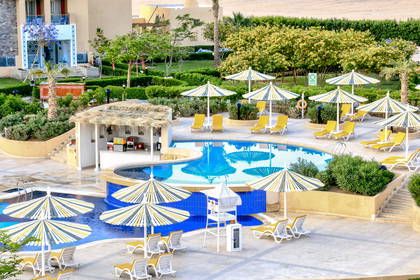 Basen hotelowy z leżakami, parasolami i barem.
