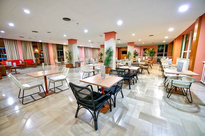 Wnętrze restauracji z drewnianymi stołami i krzesłami z plecionki.