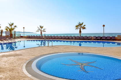 Kompleks basenów hotelowych z widokiem na ocean.