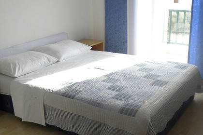 Pokój hotelowy z łóżkiem, szafkami nocnymi, telewizorem i balkonem.
