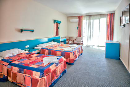 Pokój hotelowy z dwoma łóżkami, niebieskimi dodatkami i dużym oknem.