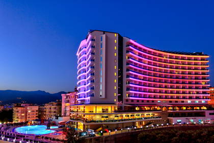 Wielopiętrowy hotel z basenem oświetlony neonami.