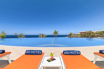 Basen w hotelu HIO z leżakami i widokiem na ocean.