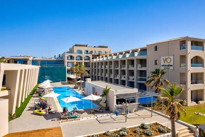 Hotel z basenem, leżakami, palmami i barem widziany z góry.