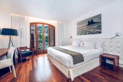 Pokój hotelowy z łóżkiem, oknem balkonowym i drewnianą podłogą.