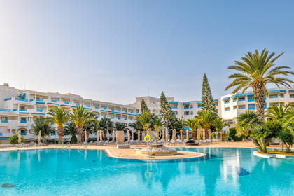 Kompleks hotelowy z basenem i palmami.