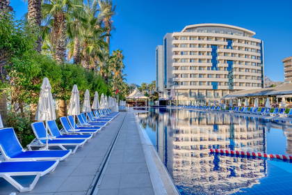 Basen z leżakami w ośrodku wypoczynkowym. W tle budynek hotelu.