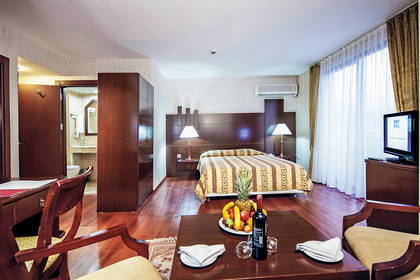 Pokój hotelowy z łóżkiem, biurkiem i owocami.