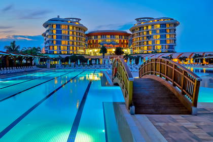 Hotel z basenem i drewnianym mostkiem o zmierzchu.