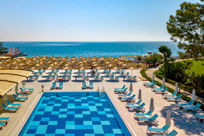 Widok z góry na basen, leżaki i parasole na plaży.