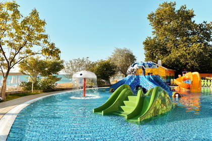 Aquapark z kolorowymi zjeżdżalniami i turkusowym basenem.