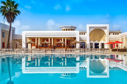 Kompleks hotelowy z basenem i jego odbicie w wodzie.