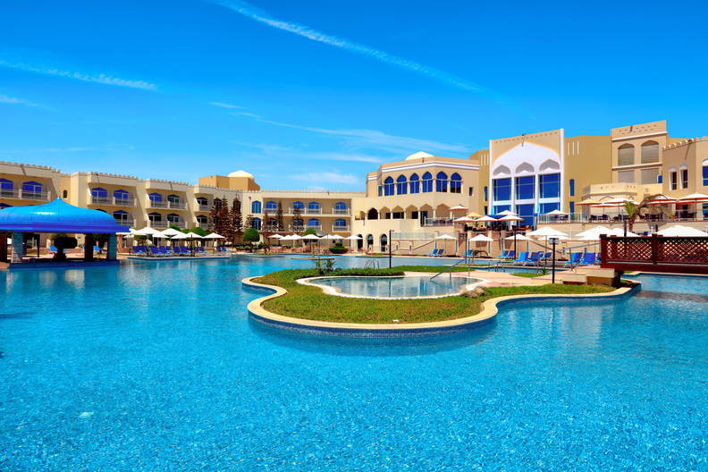 Kompleks hotelowy z basenem w słoneczny dzień.