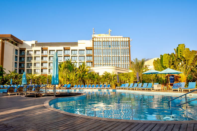 Hotel z basenem, leżakami i parasolami przeciwsłonecznymi.