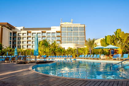 Hotel z basenem, leżakami i parasolami przeciwsłonecznymi.