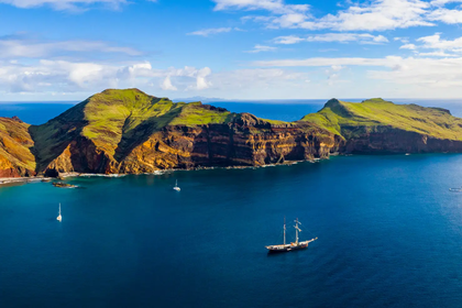 Panorama oceanu z klifami i żaglówkami na horyzoncie.