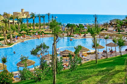 Duży basen w kurorcie z widokiem na plażę i zamek.