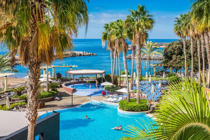 Kompleks hotelowy z basenami i palmami, w tle ocean.