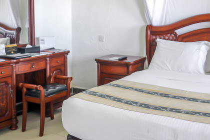 Pokój hotelowy z drewnianym łóżkiem i biurkiem.