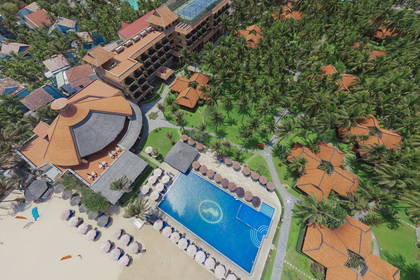Ośrodek wypoczynkowy z basenem, plażą i palmami, widok z lotu ptaka.