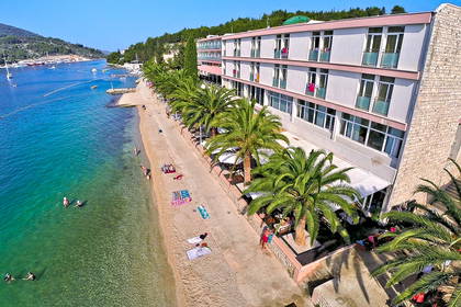 Hotel przy plaży z palmami i krystalicznie czystą wodą, widok z lotu ptaka.