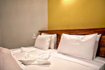 Łóżko w pokoju hotelowym z białymi poduszkami i ręcznikami.