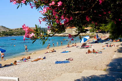 Plaża z turkusową wodą, na której ludzie pływają i się opalają.