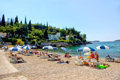 Plaża z parasolami, leżakami i wypoczywającymi ludźmi w słoneczny dzień.