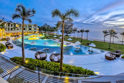 Hotel z basenem, palmami i widokiem na ocean.