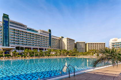 Kompleks hotelowy z basenem otoczonym palmami.