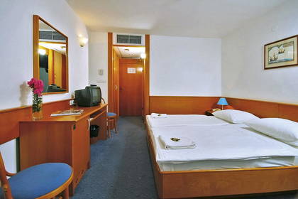 Pokój hotelowy z dużym łóżkiem, biurkiem i telewizorem.