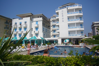 Hotel Heron z basenem i odpoczywającymi gośćmi.
