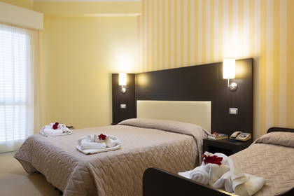 Pokój hotelowy z dwoma łóżkami i ręcznikami ułożonymi w kształt łabędzi.