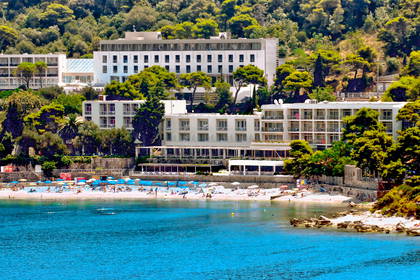 Hotel przy plaży z turkusową wodą i parasolami.